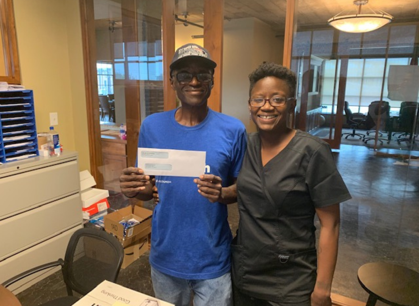 Photo of two people standing with an envelope in the mans hand.