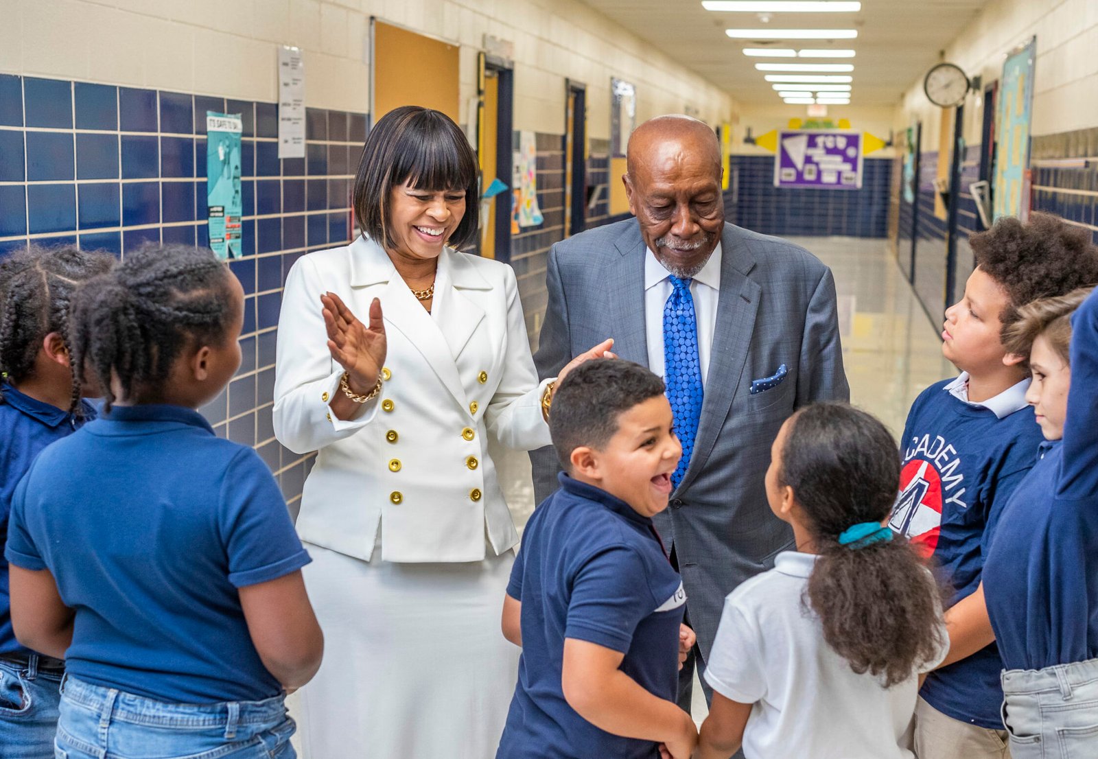 Photo of two adults talking to a group of kids.